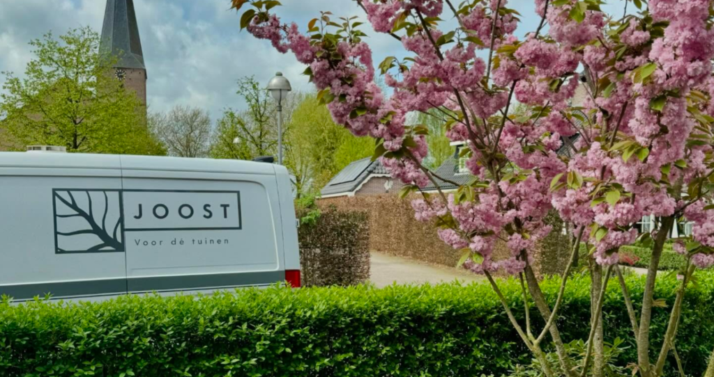 Joost voor de Tuinen professioneel aan het werk in een groene tuin met gereedschap en planten.